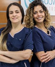 Dos mujeres con uniformes médicos posan sonriendo frente a un letrero de "Sud Laser Centro Dental".