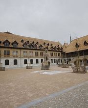 Großer gepflasterter Platz mit historischem Gebäude im Hintergrund unter grauem Himmel.
