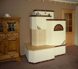 Kachelofen in einem Wohnzimmer mit Holzmöbel und Teppichboden, braun-weiße Optik.