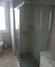 Ducha de vidrio en un baño moderno con luz natural entrando por la ventana.