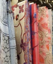 Verschiedene bunte Schals hängen an Kleiderbügeln.