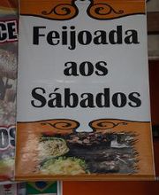 Placa com texto: "Feijoada aos Sábados" e imagem de pratos coloridos ao fundo.