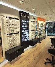 Winkelinterieur met brillen displays, houten vloer en stoelen.