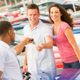 Man handing car keys to a smiling couple at a dealership.