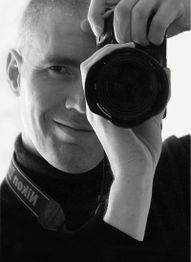 Mann fotografiert mit Kamera im Spiegel, Nikon-Trageriemen sichtbar, schwarz-weiß Foto.