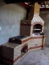 Churrasqueira de alvenaria em canto de parede, com forno e fogão integrados, piso de concreto.