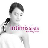 Mujer con toalla y masajeador, logo "intimissis.es" y texto "exciting love". Imagen en blanco y negro.