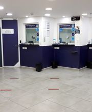 Sala de espera de um escritório com cadeiras, mesas de atendimento e paredes decoradas.