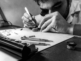 Orologiaio concentrato su piccoli ingranaggi al tavolo da lavoro, con attrezzi specializzati.