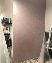 Pared decorada en tonos rosados con estantes de productos de peluquería al lado.