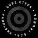 Logotipo circular con el texto "Gure Etxea, Pamplona 1975 Iruñea" y un diseño de espiral.