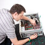Man repairing electronic device with tools on a table.