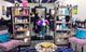Salon interior with shelves of hair products, two chairs, and a table with magazines and flowers.