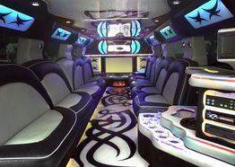 Luxurious limousine interior with LED lights, spacious seating, and a small bar area.