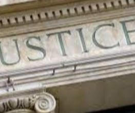 Scritta "JUSTICE" su un edificio di pietra.