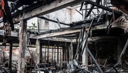 Charred remains of a burned-down building with damaged beams and debris inside.