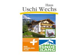 Gebäude „Haus Uschi Wechs“ in den Bergen mit Bad Hindelang Plus Logo.