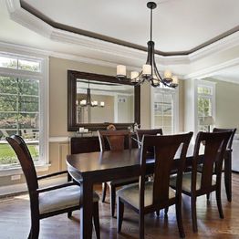 Elegant dining room with wooden table, six chairs, chandelier, large windows, and a wall mirror.