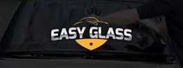 Pare-brise sombre avec logo "Easy Glass" en blanc et or; une main nettoie la vitre.