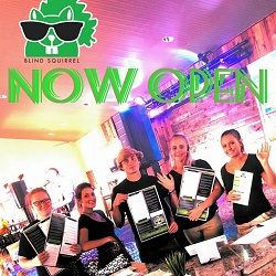 Group of five smiling staff holding menus at "Blind Squirrel" restaurant, under "Now Open" text.