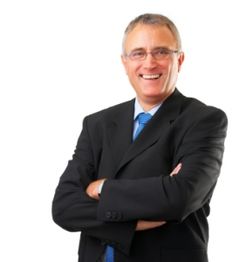 Smiling man in a suit with arms crossed against a white background.