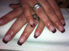 Zwei Hände mit rot-weißer Maniküre, schimmernden Ringen, auf einem weißen Handtuch.