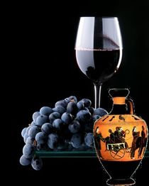 Weintrauben, ein Glas Rotwein und antike griechische Vase vor schwarzem Hintergrund.