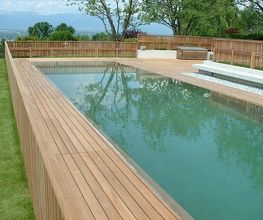 Holzumrandeter Swimmingpool in einem Garten mit Blick auf die Berge im Hintergrund.