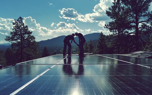 Zwei Handwerker auf einem Dach, die eine Solaranlage installieren.