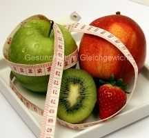 Obst mit Maßband: Grüne und rote Äpfel, Kiwi und Erdbeere auf einem Teller.