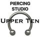 Afbeelding met tekst "Piercing Studio Upper Ten" en een cirkelvormige piercing.