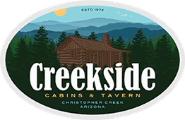 Creekside Cabins & Tavern logo with a cabin in a forest setting and mountains in the background.