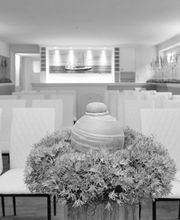 Reihen weißer Stühle in einem modernen Raum, dekoriert mit Bildern und Pflanzenarrangement.