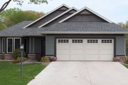 Gray house with double garage, gabled roof, and front lawn.