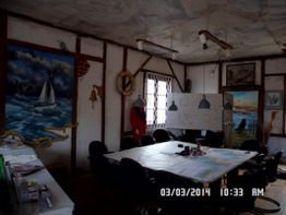 Ein Raum mit nautischen Wandgemälden und Tisch in der Mitte, umgeben von Stühlen.