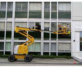 Gelber Hubsteiger steht vor einem Gebäude, Arbeiter sind in der Gondel in Höhe der Fenster.