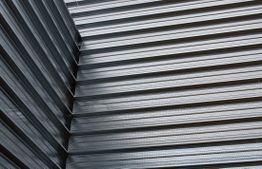 Corrugated metal wall with intersecting lines creating an industrial pattern.