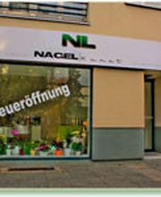 Geschäftsfassade mit "Neueröffnung" auf dem Schaufenster und grüner Dekoration.