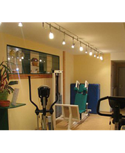 Kleines Fitnessstudio mit Geräten und dekorativen Pflanzen, hell erleuchtet.