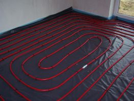 Fußboden mit rotem Rohrsystem für Fußbodenheizung in einem leeren Raum.