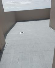 Azotea vacía con suelo de concreto gris, cielo parcialmente nublado.