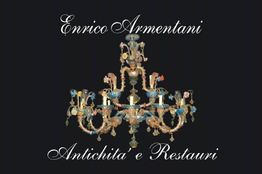 Lampadario antico decorativo con testo "Enrico Armentani Antichità e Restauri". Sfondo nero.