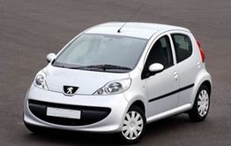 Silberner Peugeot-Kleinwagen auf einer Straße.