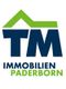 Logo von TM Immobilien Paderborn mit stilisiertem grünen Dach über den Buchstaben "TM".