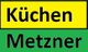 Gelbes Schild mit "Küchen" in Schwarz, darunter grünes Schild mit "Metzner" in Schwarz.