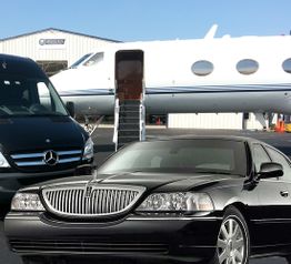 Private jet on tarmac with a black limousine and van in the foreground.