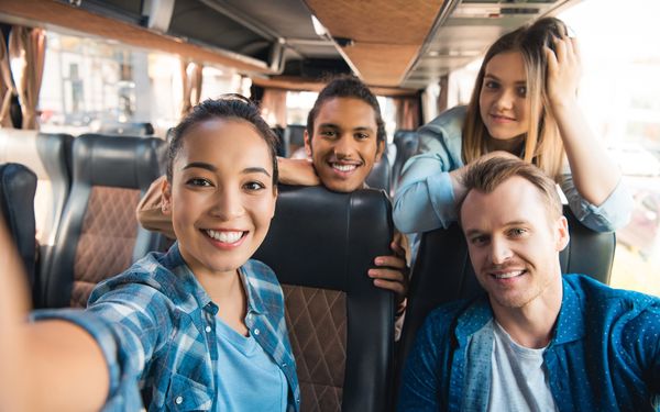 Vier junge Menschen machen ein Selfie während sie in einem Reisebus sitzen