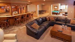 Cozy lounge with a leather sofa, bar, and games room featuring billiards and ping-pong.