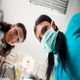 Two dental professionals wearing masks and goggles, seen from a patient's perspective.