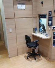 Corredor com mesa e cadeira de escritório em canto iluminado, perto de porta azul com números.